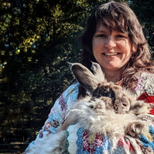 A woman wearing a quilt coat and holding an angora rabbit