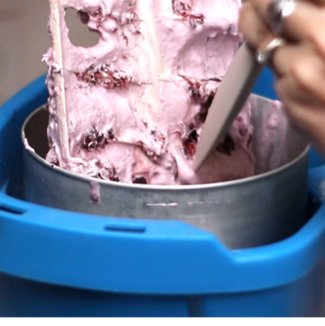 Blackberry ice cream in an ice cream machine. across the photo is the text: blackberry ice cream. step by step recipe.