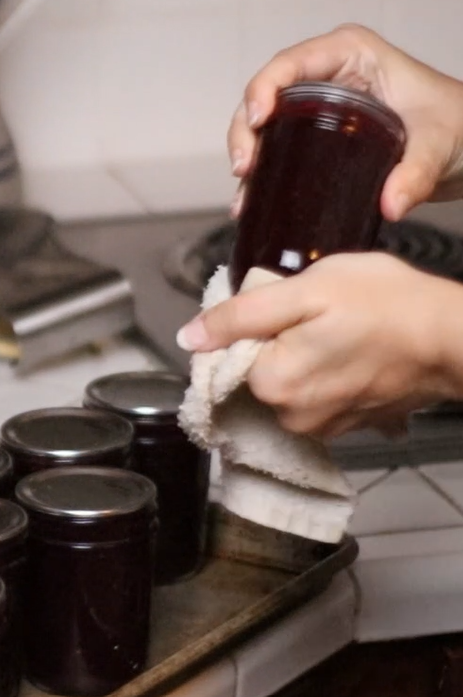 a person wiping down a jar of jam