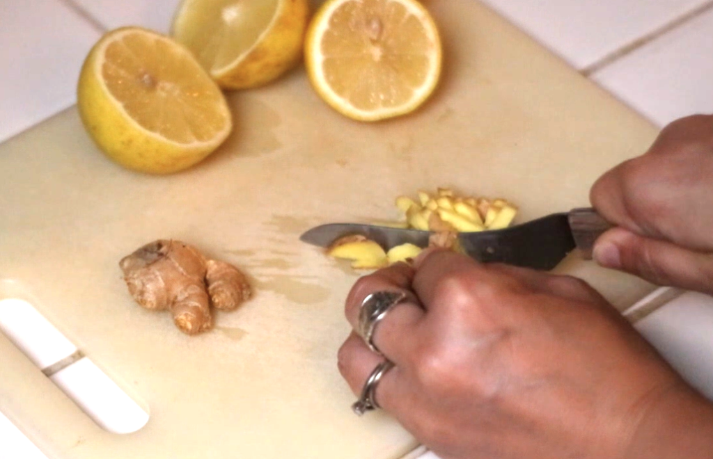 a cutting board with lemon halves and fresh ginger being chopped