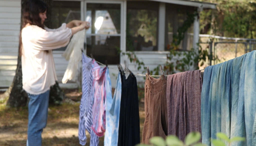 a woman hanging laundry on a clothesline outside