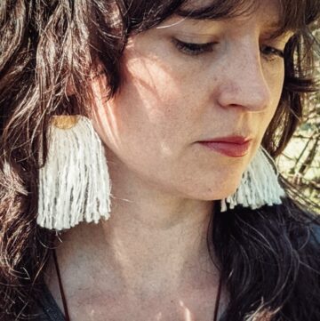a woman wearing tassel earrings made of handspun white angora yarn