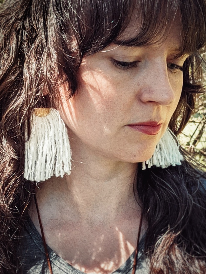 a woman wearing tassel earrings made of handspun white angora yarn
