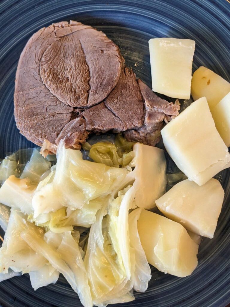 a dinner plate with sliced corned venison, cooked cabbage, and potatoes