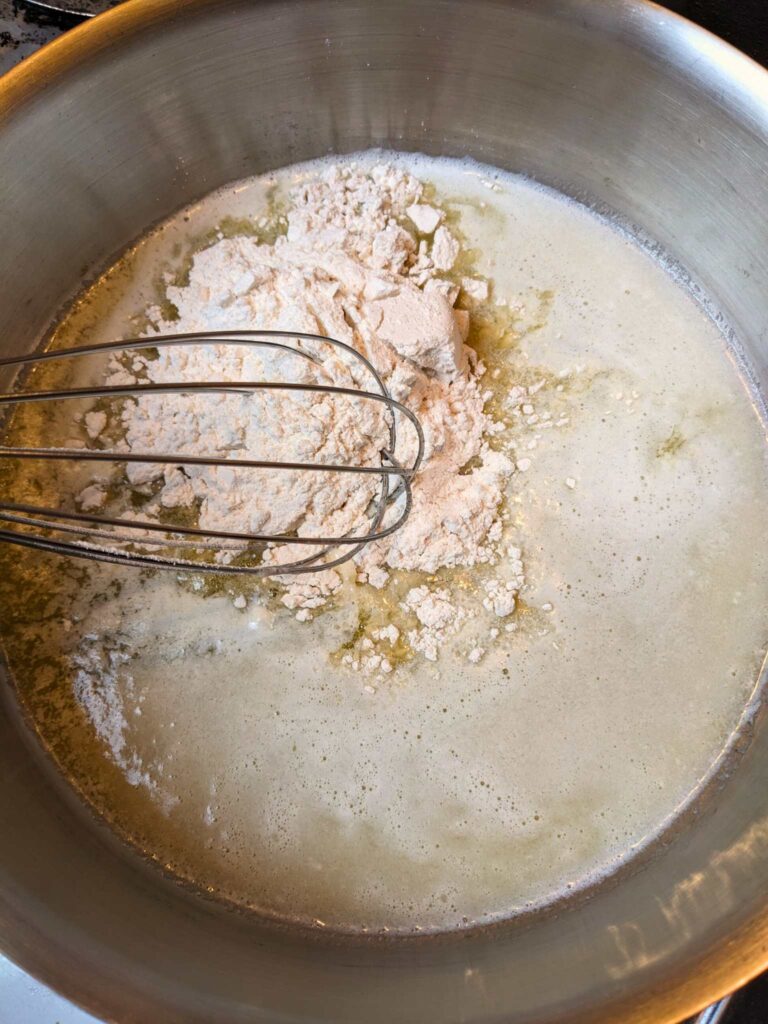 whisking flour into melted butter to make a roux for creamed eggs on toast