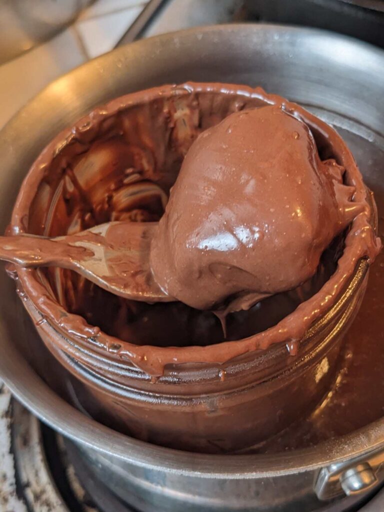 dipping a square of almond joy filling in melted chocolate