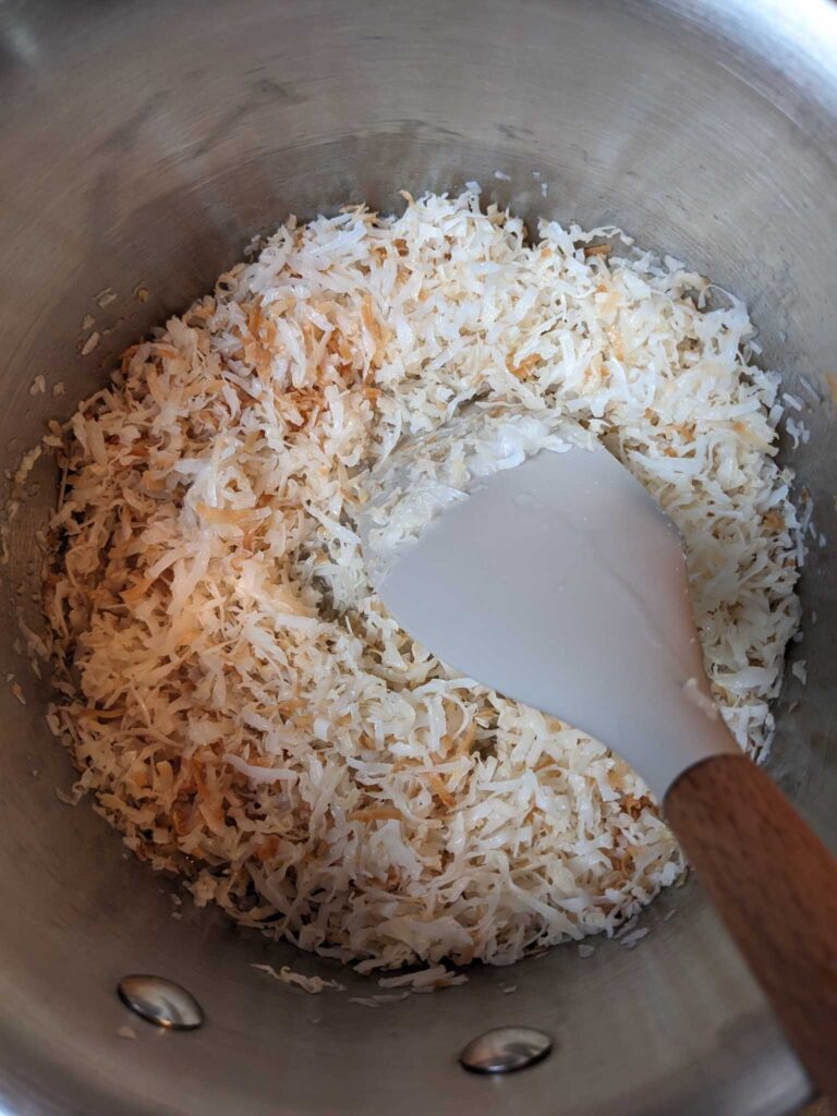 toasting shredded coconut in coconut oil to make homemade almond joy candy bars
