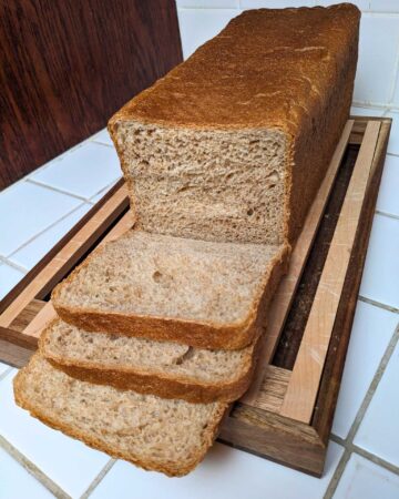 a loaf of whole wheat pain de mie bread, partially sliced.