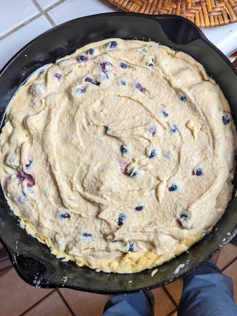 blueberry cornbread batter in a cast iron skillet