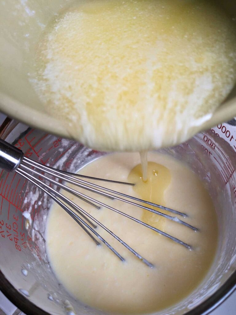 whisking melted butter into an egg and yogurt mixture to make blueberry cornbread