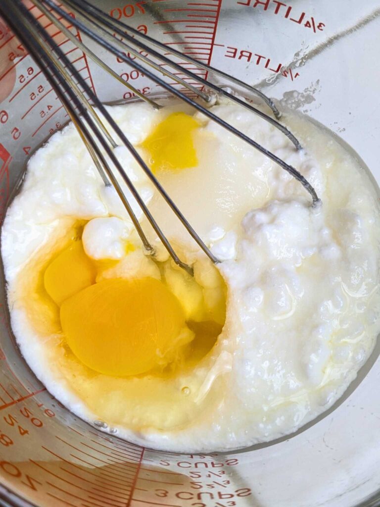 whisking eggs and yogurt together to make blueberry cornbread