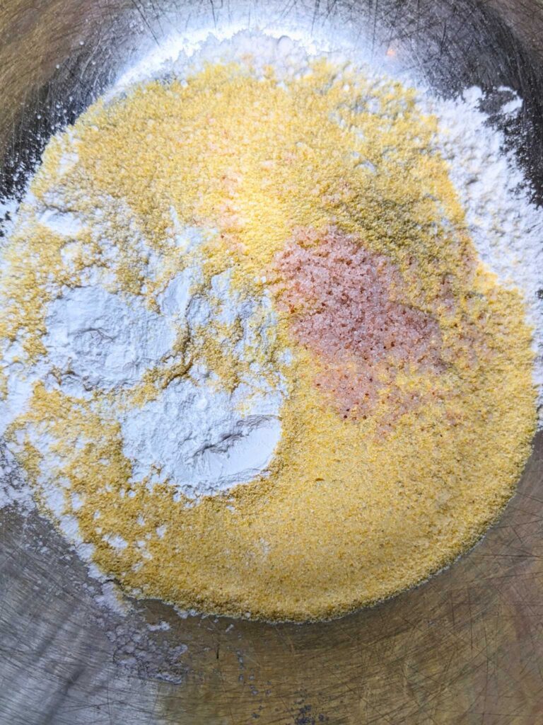 mixing cornmeal, flour, salt, and baking soda together to make blueberry cornbread
