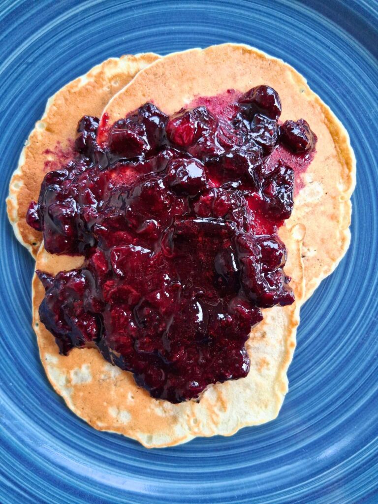 blueberry compote topping a plate of pancakes