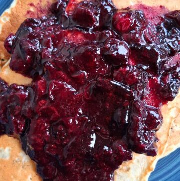 a plate with pancakes and blueberry compote on it.