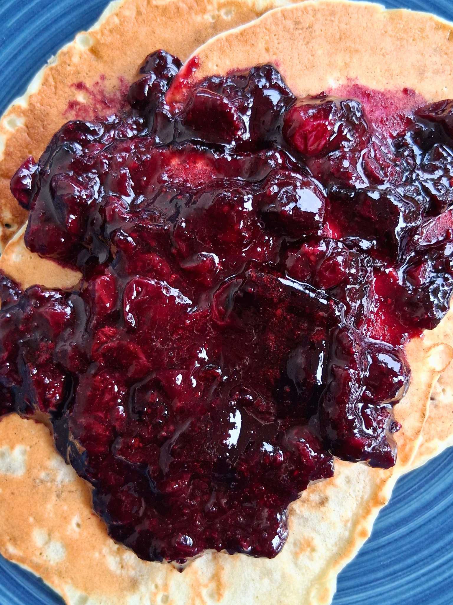 a plate with pancakes and blueberry compote on it.