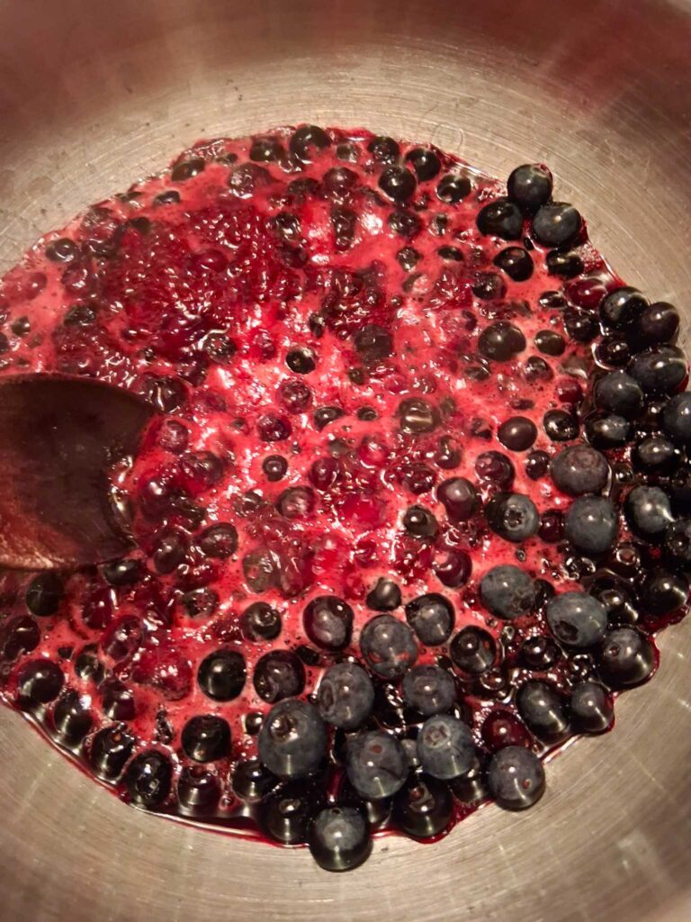 a pot of blueberry compote being stirred and simmered
